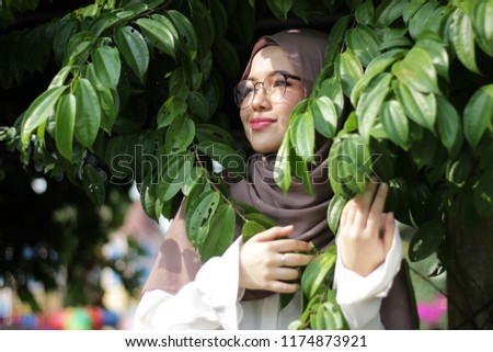 cute lady with hijab style portrait shoot at tree and leaf of nature