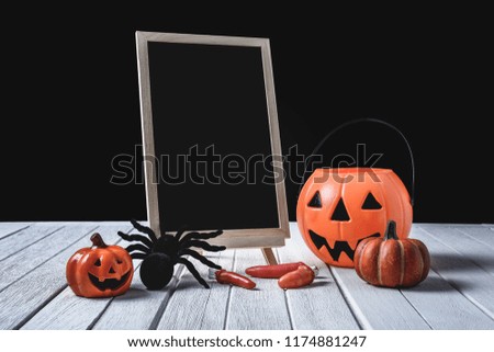The chalkboard on the stand with Halloween Pumpkins, Black spider and finger on white wooden floor halloween background