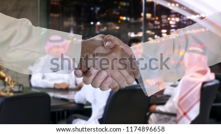 Handshake multi exposure with Saudi Arab businessmen meeting in the background Royalty-Free Stock Photo #1174896658