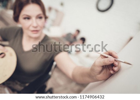Disabled Soldier In Wheelchair Draws A Picture. After War Concept. Camouflage Uniform. Paralyzed Woman With Tassel. Home Leisure. Return From Army. Family Background. Husband And Son.