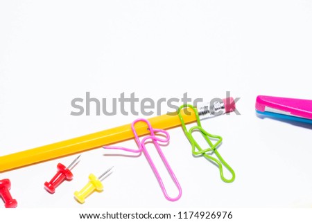 Two paper clips talking while lying on a white floor and on a pencil. Miniature school life and back to school concept with copy space white background. 