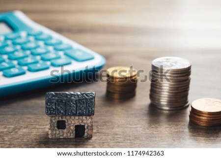 House model, stack of coins and calculator. Concept in house selling, buying, loan and finance business.