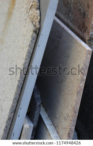 Close up outdoor view of marble slabs of different colors: grey, white, black, pink. Several thin granite polished sheets standing vertically. Abstract image of decorative gravestones for cemetery.  