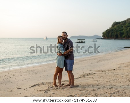A man and a girl are hugging on the beach
