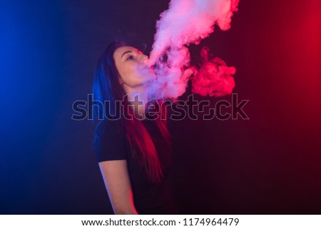 Portrait of asian woman smoking vape or e-cigarette in neon light at black background.