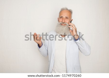 Studio shot of happy senior bearded businessman smiling while using mobile phone with  against white background