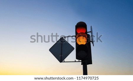 Traffic light with red and yellow signals on blue sky background