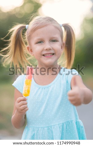 Little beautiful girl eating outdoors ice cream in the park