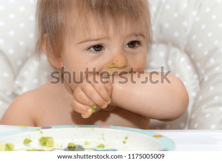 Messy And Dirty Sweet Baby Is Eating Avocado With Hands. Portrait Photography