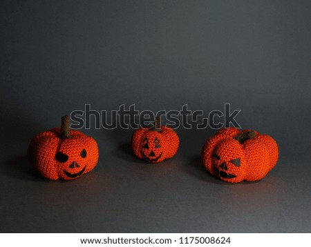 Halloween knitted pumpkins with funny faces on dark grey background. Halloween ideas.
