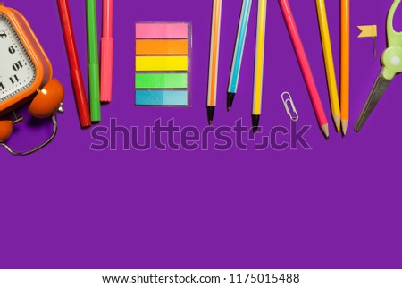 row of multiple school and office supplies and gadgets lying on a purple background. free space for advertising text