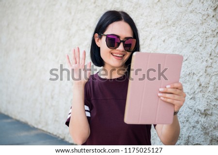 Self portrait of cheerful positive girl shooting selfie on front camera, having video-call with friend