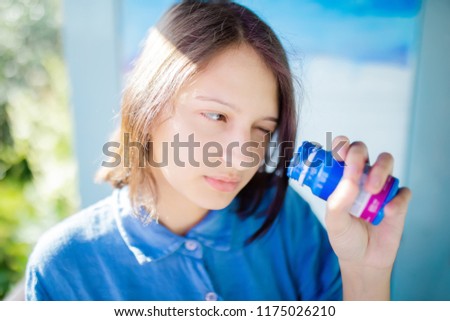 Beautiful smiling girl artist draws a picture, holding and looking inside blue paint jar paint jar, artistic people