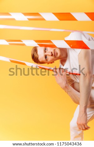 redhead man in white on yellow background  with  red and white ribbon. Prohibition concept. Breaking rules concept. No way concept. Stop. Obsticle
