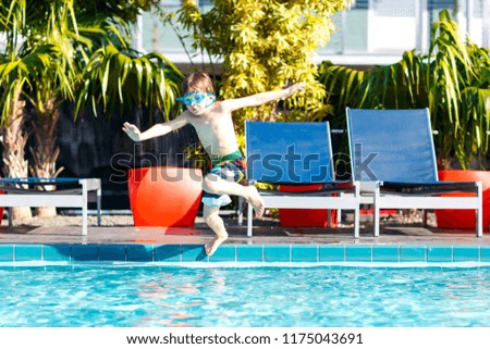 Happy little preschool kid boy jumping into water at pool. Child having fun in an swimming pool. Active happy child winning. sports, active leisure for children.