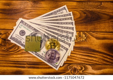 Bitcoin, microprocessor and one hundred dollar bills on rustic wooden table. Top view