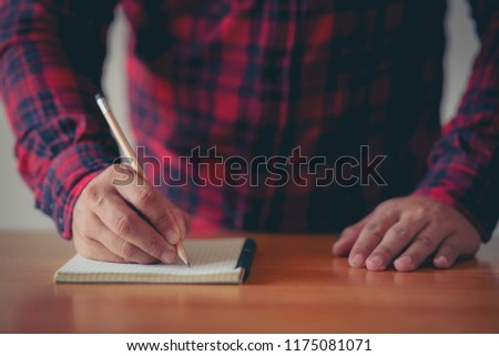 Man hand writing something on notebook