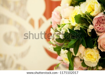A beautiful pink and yellow wedding bouquet with ornament on the background.