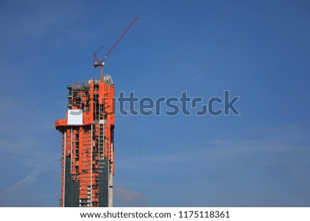 Crane and high building construction site against blue sky