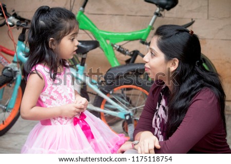 Little Indian girl talking with her mother on patio Royalty-Free Stock Photo #1175118754