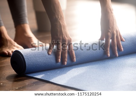 Meditation session, fitness healthy mindful lifestyle concept. Hands of fit woman rolling fitness, pilates, yoga mat before or after working out in yoga studio club or at home on floor. Close up view Royalty-Free Stock Photo #1175120254