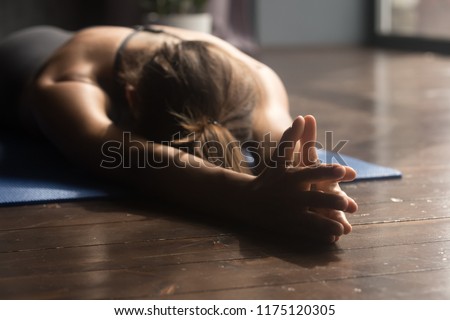 Young sporty attractive woman practicing yoga, doing breathing exercise, relaxation pose, working out, wearing sportswear, indoor close up, yoga studio Royalty-Free Stock Photo #1175120305