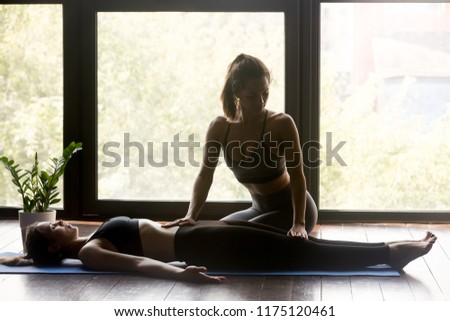 Young beautiful sporty women wearing sportswear practicing yoga exercise, yogi therapist helping yoga student, after working out, yoga indoor studio, girl training in sport club with instructor Royalty-Free Stock Photo #1175120461