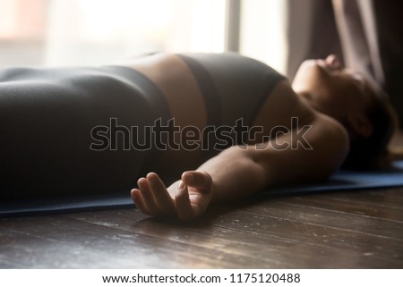 Young sporty woman practicing yoga, doing Dead Body, Savasana exercise, Corpse pose, working out, wearing sportswear, grey pants and top, indoor close up view, yoga studio, focus on mudra gesture Royalty-Free Stock Photo #1175120488