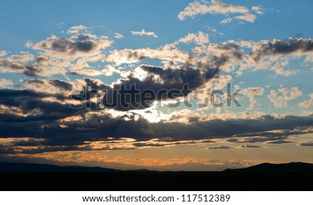 Sun rays at sunset in the clouds on the mountains