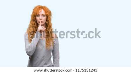 Young redhead woman asking to be quiet with finger on lips. Silence and secret concept.