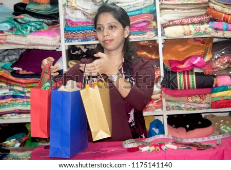 Woman entrepreneur handling over shopping bags to customer at boutique Royalty-Free Stock Photo #1175141140