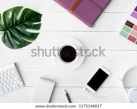 top view of graphic design concept with smartphone, pantone book, coffee cup and keyboard on white table background.