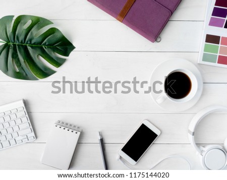 top view of graphic design concept with smartphone, pantone book, coffee cup and keyboard on white table background with copy space.