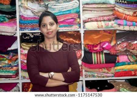 Portrait of boutique owner with arms crossed in front of clothes shelf Royalty-Free Stock Photo #1175147530