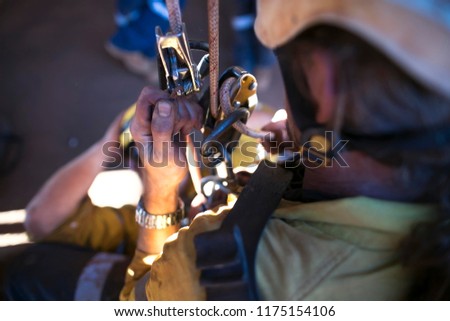 Picture rope access worker hand holding secondary safety back up device, and controlling descender, abseiling down with casualty during team rescue rehearsal construction site Perth, Australia 