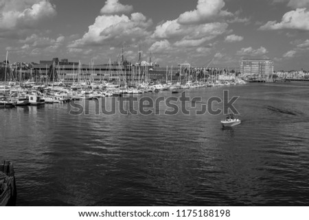 A boat sails past docked sailboats in boston harbor