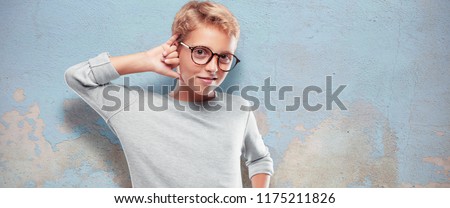 young blonde handsome boy making a phone call gesture or sign, with a proud, happy, satisfied look; offering communication with a smile.