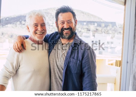 couple of men hugging and stay together in friendship and relationship. father and son different ages smi.ing and look at the camera. portrait of cheerful caucasian people mixed generations enjoy life Royalty-Free Stock Photo #1175217865