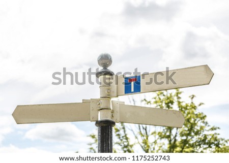 Signs on a pole indicating directions with a sky covered background, UK