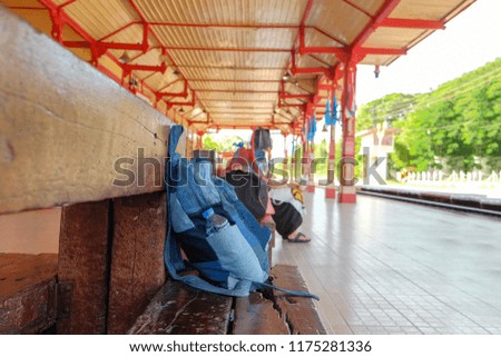 A traveling concept picture of a backpack on outdoor public seat for passenger at one of public train station ,Thailand.