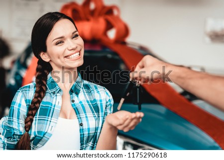 A Guy Gives A Car Key To Girlfriend. Present Concept. Automobile Salon. Make A Decision. Gift Ribbon. End Of A Deal. Good Offer. Happy Together. Successful Buying. Beautiful Surprise.