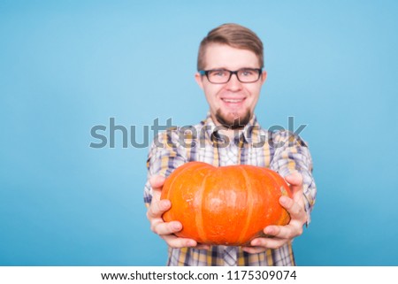 Close up of smiling man holding pumpkins over blue background, harvest concept