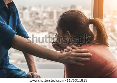 Psychologist sitting and touch young depressed asian woman for encouragement near window with low light environment, Selective focus, PTSD Mental health concept, Royalty-Free Stock Photo #1175311813