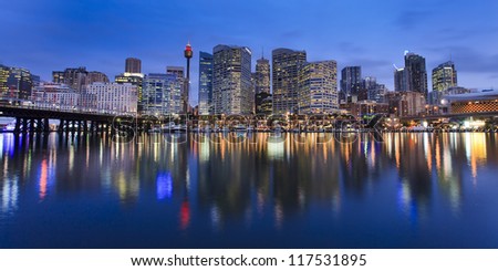 Darling Harbour bay in Sydney city panoramic view at sunset with lights illuminated in water over boats