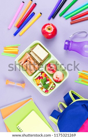School concept flat lay. Kid backpack, lunchbox, water bottle, notebook, markers on wooden desktop