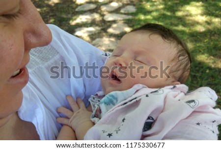 Happy Caucasian mother looking at her newborn baby child she is holding on her hands. Young mother happiness concept image.