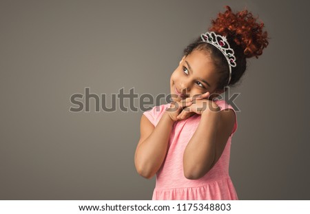 Dreamy little princess. Cute black girl in tiara at gray studio backdrop, copy space Royalty-Free Stock Photo #1175348803