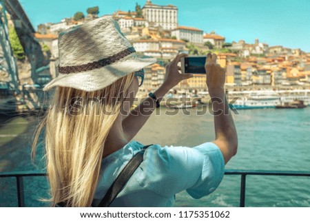 Happy blonde woman - tourist shot on her smartphone camera beautiful city view. with ships on the river in sunny day.