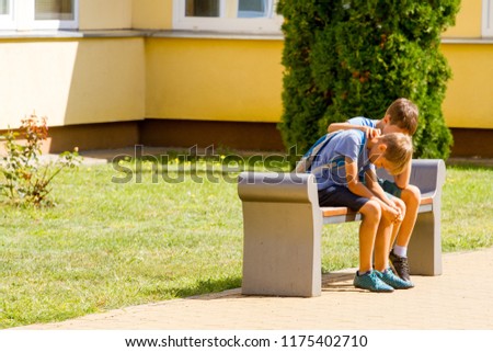 Kid comforting consoling upset sad boy in school yard Royalty-Free Stock Photo #1175402710