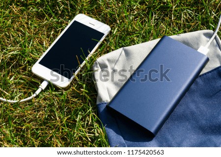 power bank charges a smartphone on the grass